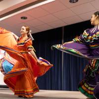 GVSU Monarcas traditional Mexican Ballet Folklorico performing on stage in purple and orange outfits.
